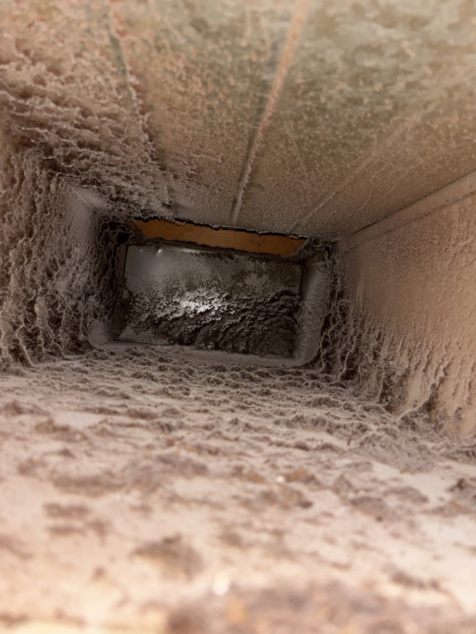 Air duct before professional cleaning showing heavy dust and debris accumulation